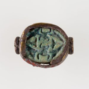 Ancient Egyptian blue glazed steatite scarab decorated with papyrus plants and winged beetles symbolizing rebirth and protection.