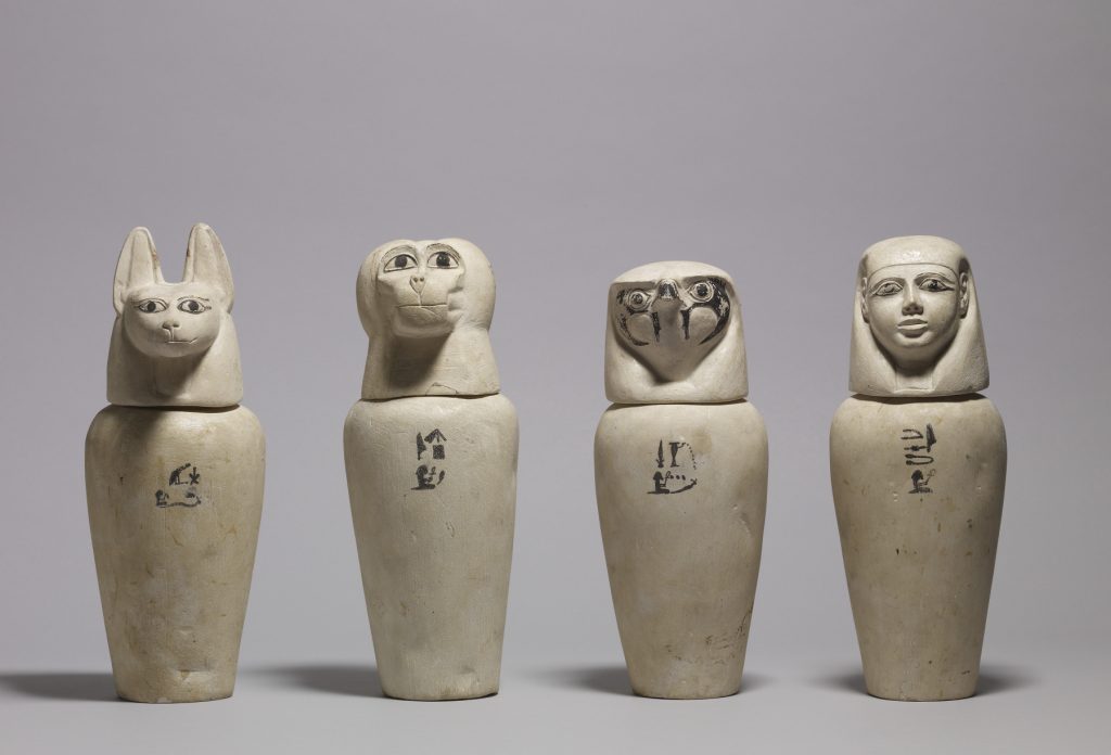 A complete set of ancient Egyptian canopic jars with jackal, baboon, falcon, and human-headed lids representing the Four Sons of Horus.